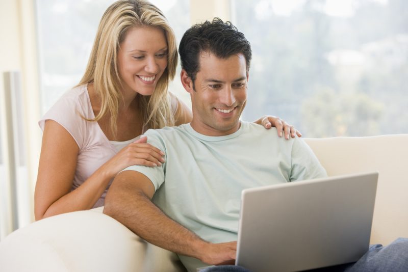 couple-in-living-room-using-laptop-smiling