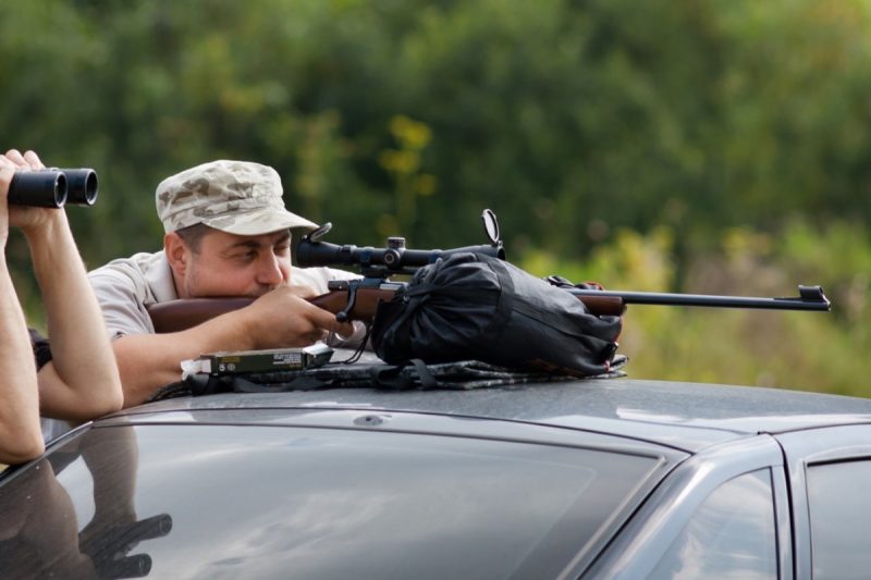the-shooter-aiming-from-a-rifle-and-his-friend-looking-through-binoculars